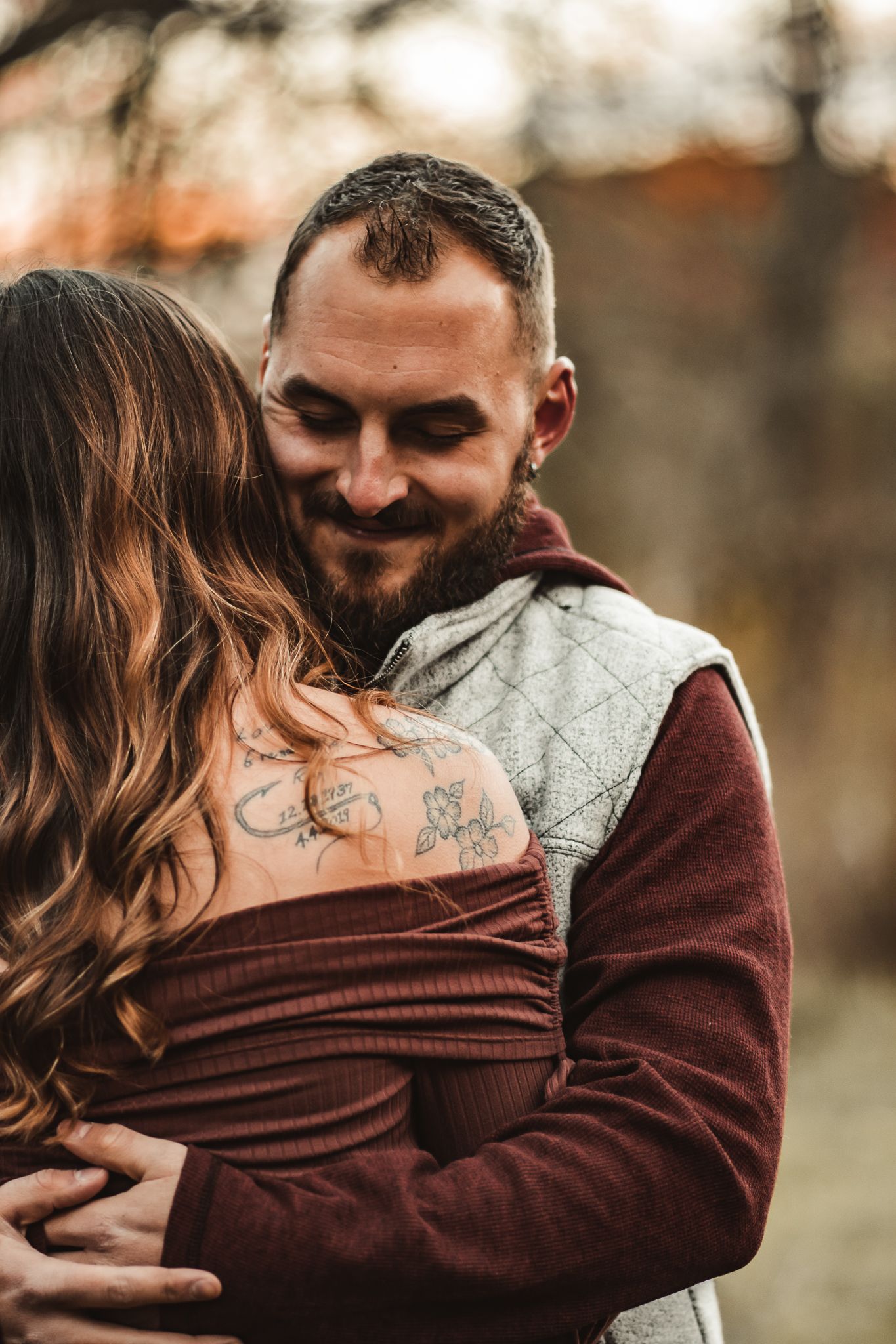 Intimate close-up of couple embracing, showing visible tattoo detail.