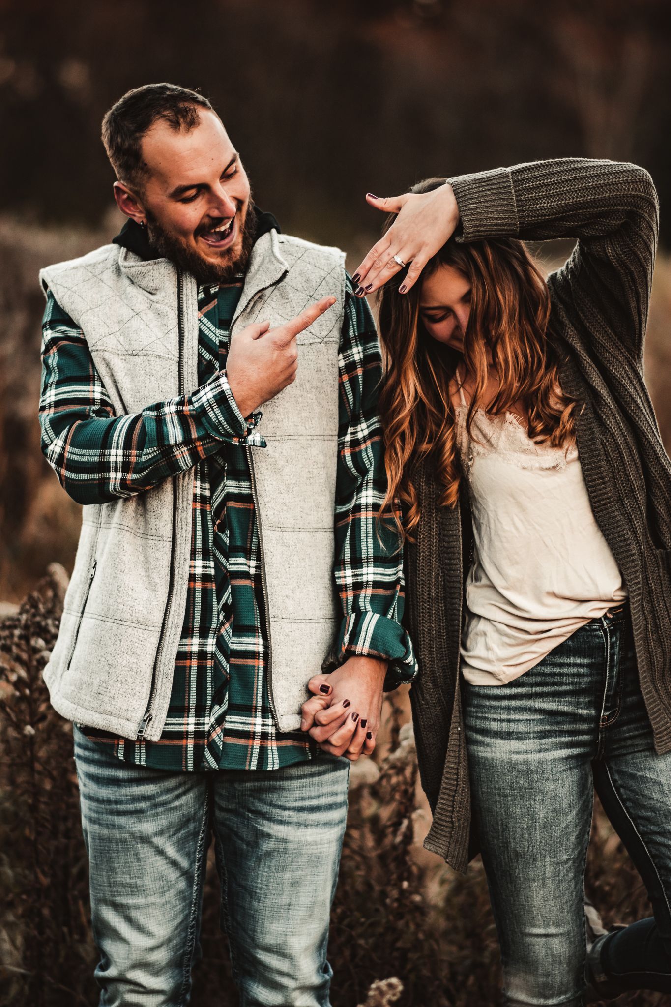A playful and joyful couple sharing a laugh in a rustic outdoor setting.