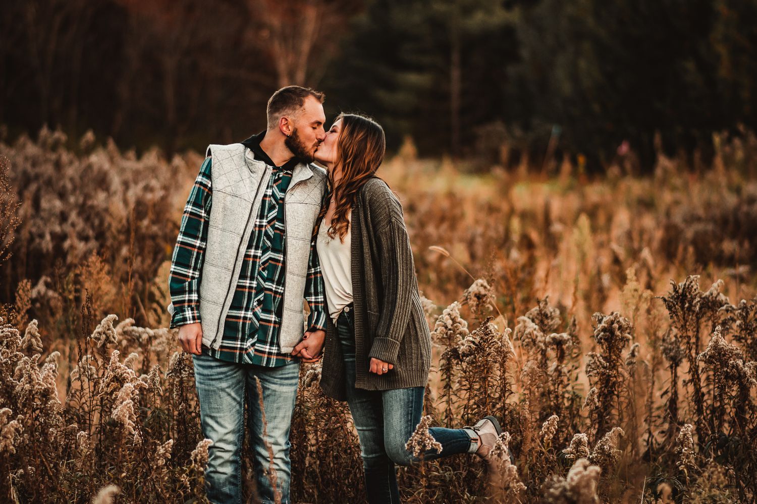 A tender moment between a couple standing in a golden field during autumn.
