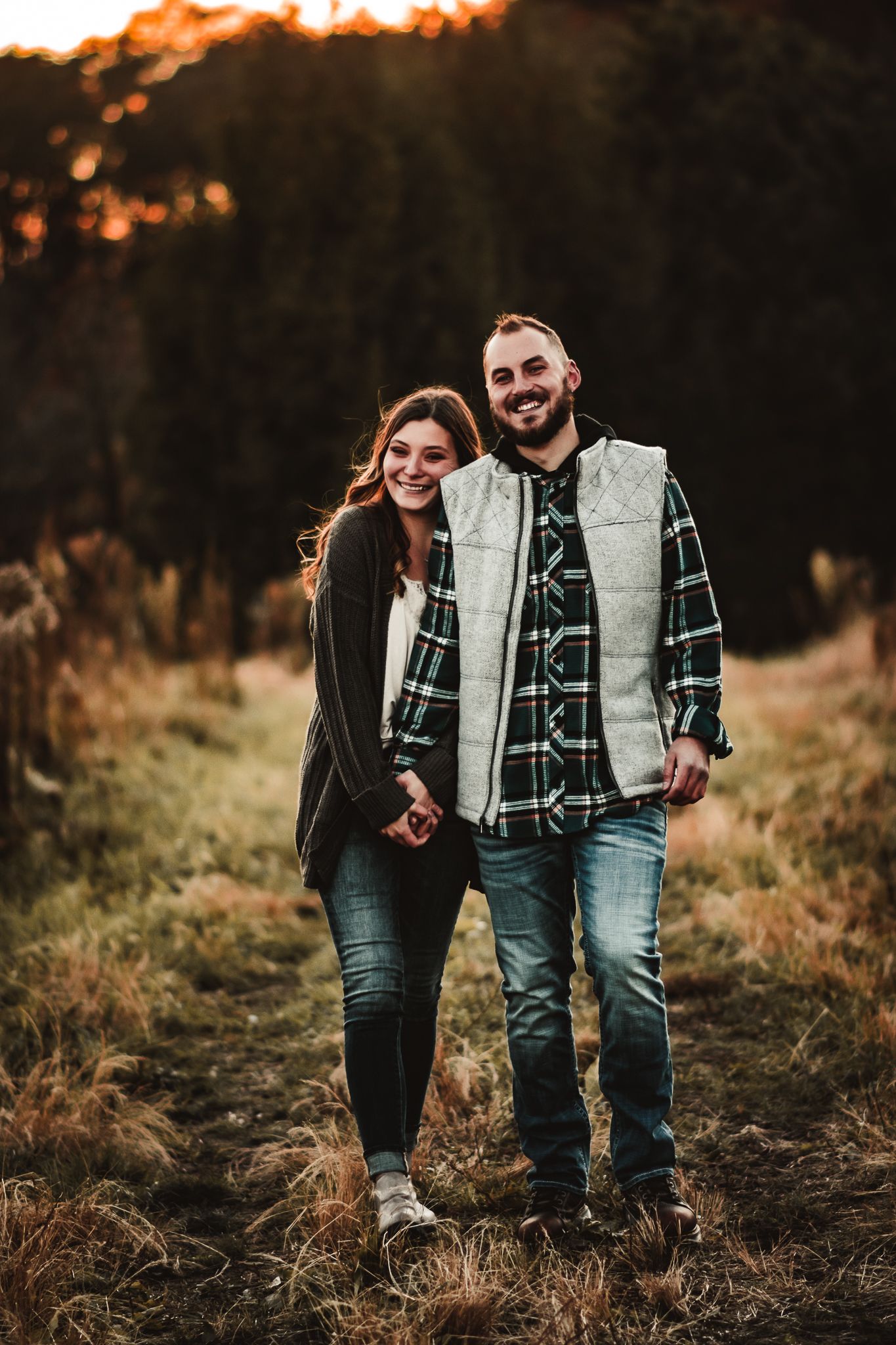 A happy couple walking together on a trail during autumn sunset.