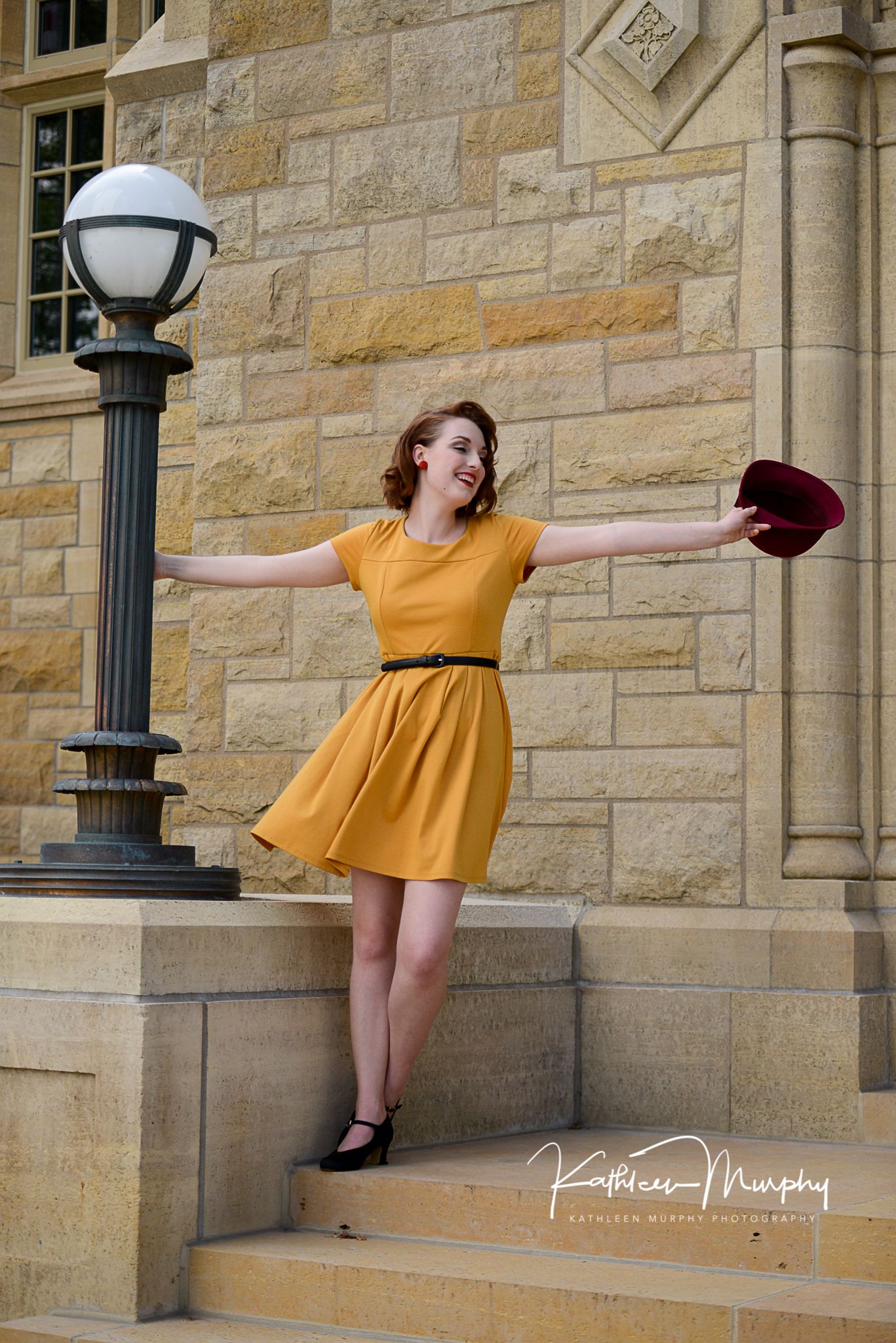 A retro-inspired fashion pose on stone steps next to a vintage street lamp.