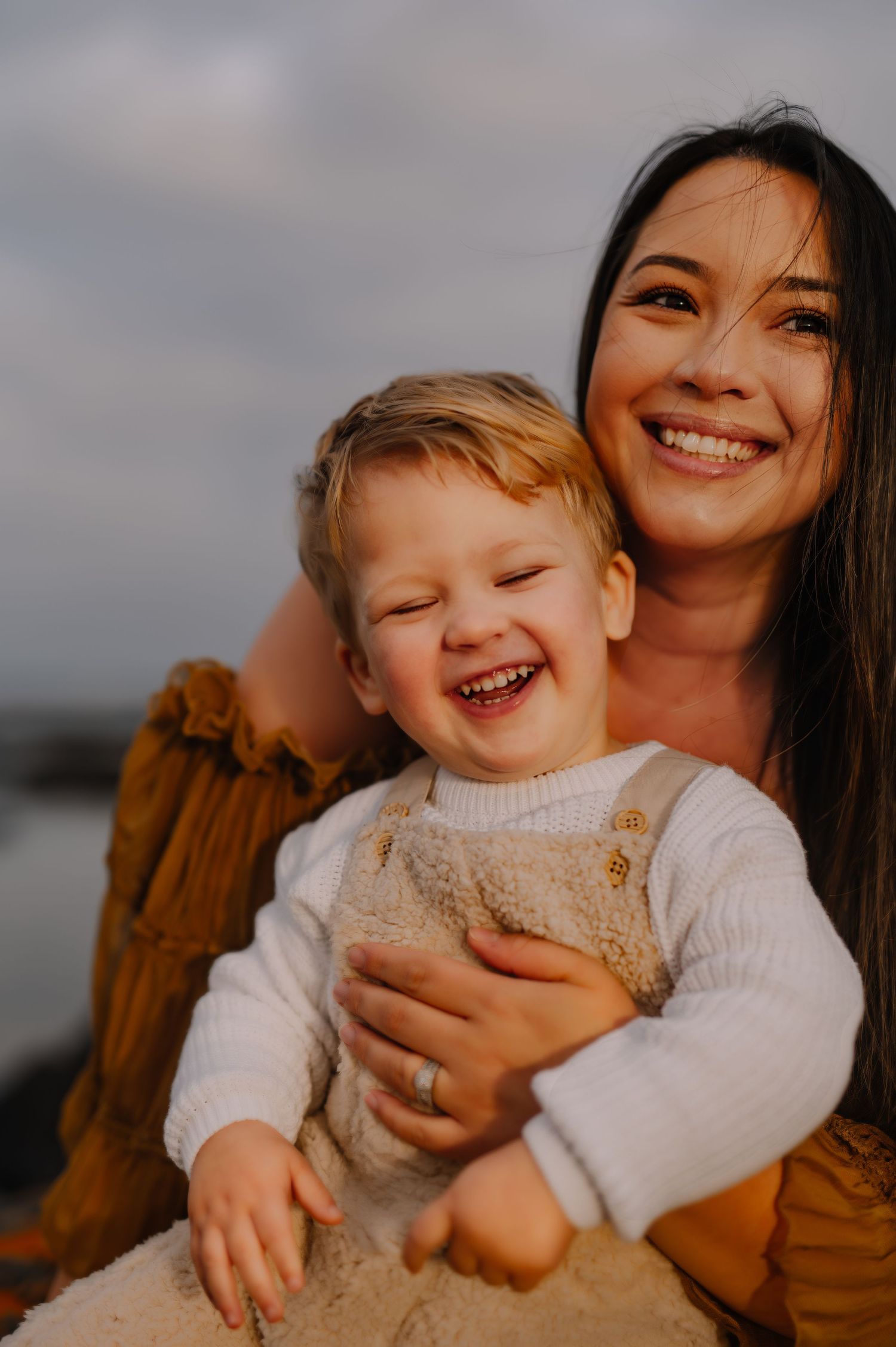 A joyful moment captured between parent and toddler laughing together outdoors at sunset.