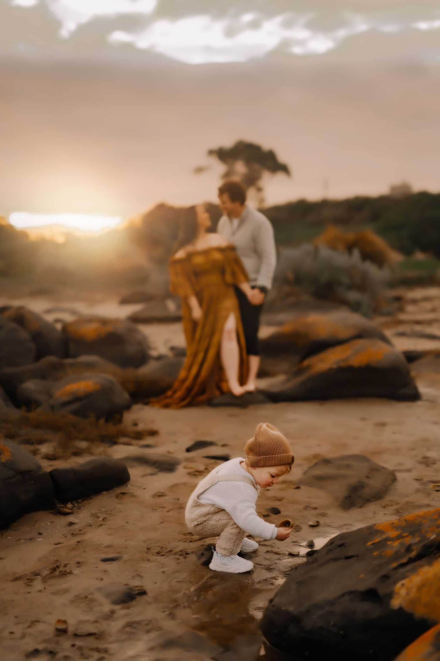 A scenic beach photo at sunset with figures exploring among rocky formations.