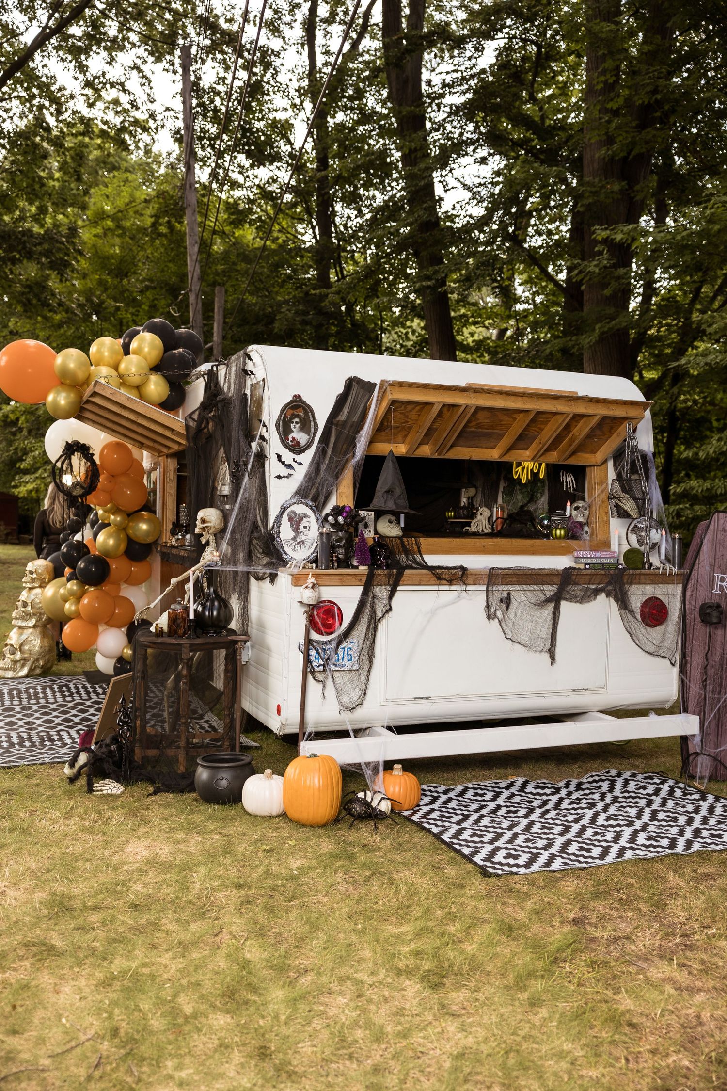 Halloween-themed mobile bar with balloon decorations and gothic accents in an outdoor setting.