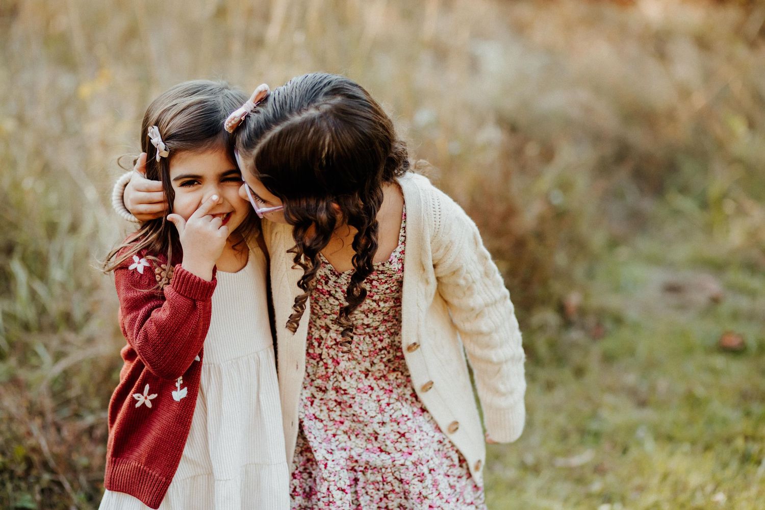 Two people sharing laughter and embracing in a sun-drenched field.
