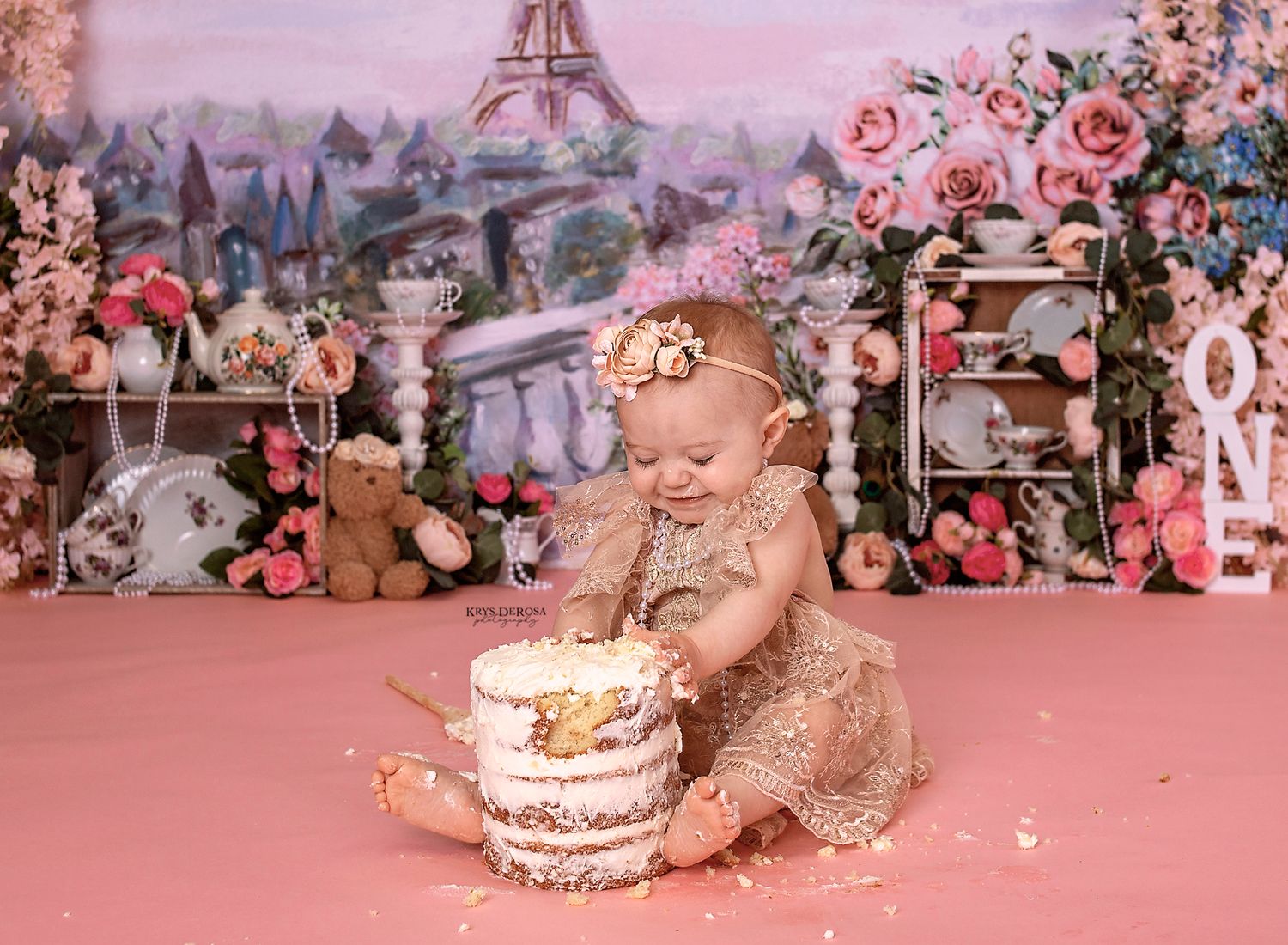 Cake smash session with Paris backdrop featuring roses and whimsical decor.