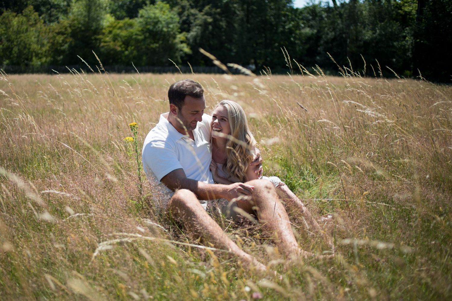 Engaged couple in field laughing and enjoying being with each other