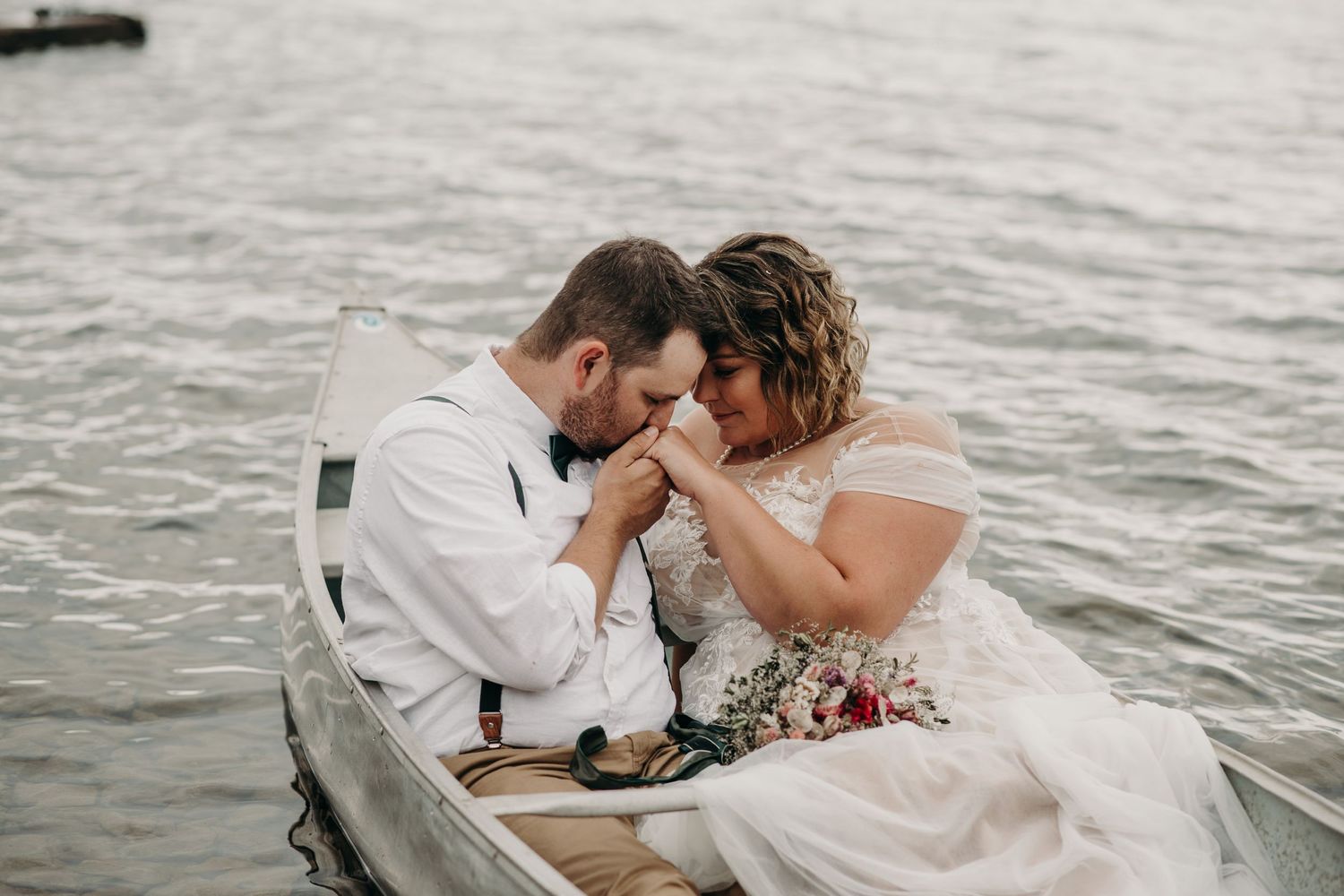 groom kissing brides hand on a boat in the water