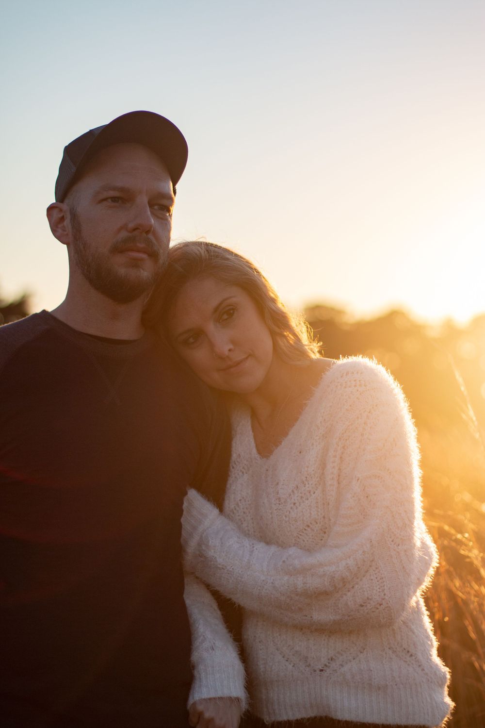 A couple rests on each other lovingly during golden hour