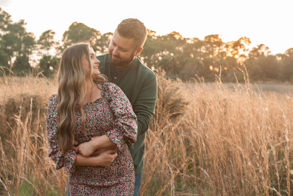 Couple smiling at each other in field in Stuart, Florida