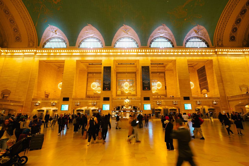 Golden illuminated interior of Grand Central Terminal's main concourse during busy hours.