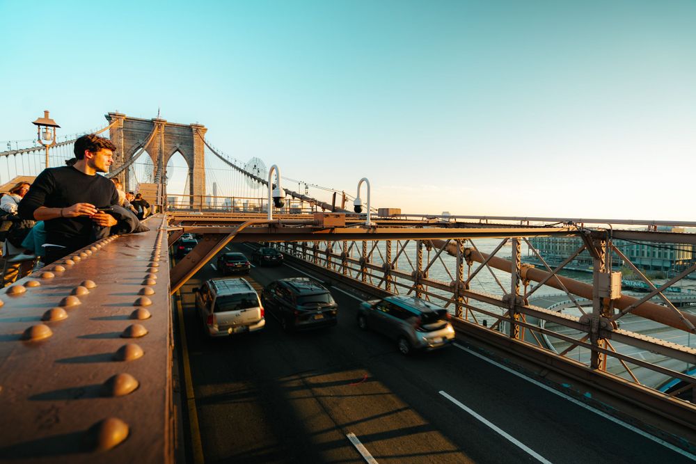 Sunset view of the Brooklyn Bridge with warm lighting and traffic lanes.