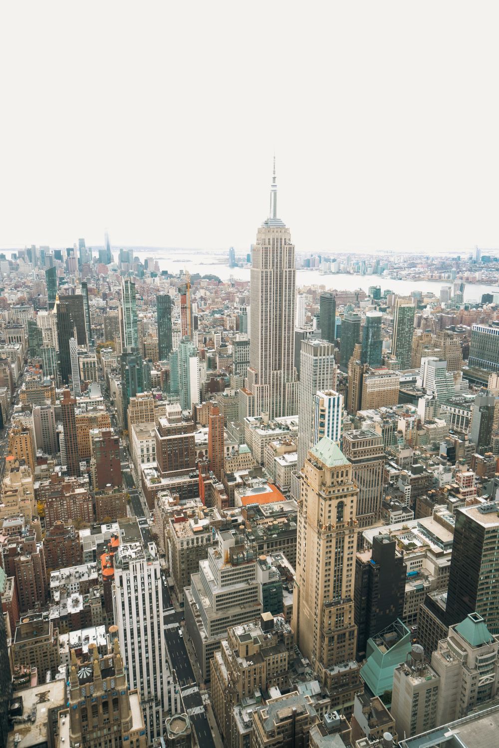 Panoramic aerial view of Manhattan skyline showing Empire State Building and surrounding skyscrapers.