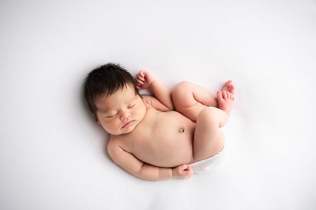Newborn baby girl unposed in a white wrap womb like.