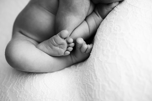 Black and white image of newborn baby girl focused on her toes.