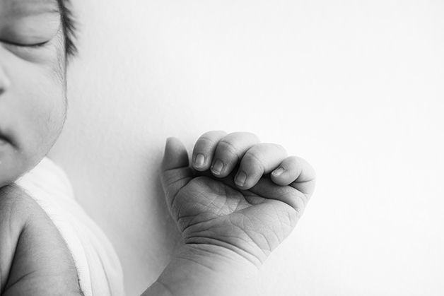 Black and white image of newborn baby girl's hand.