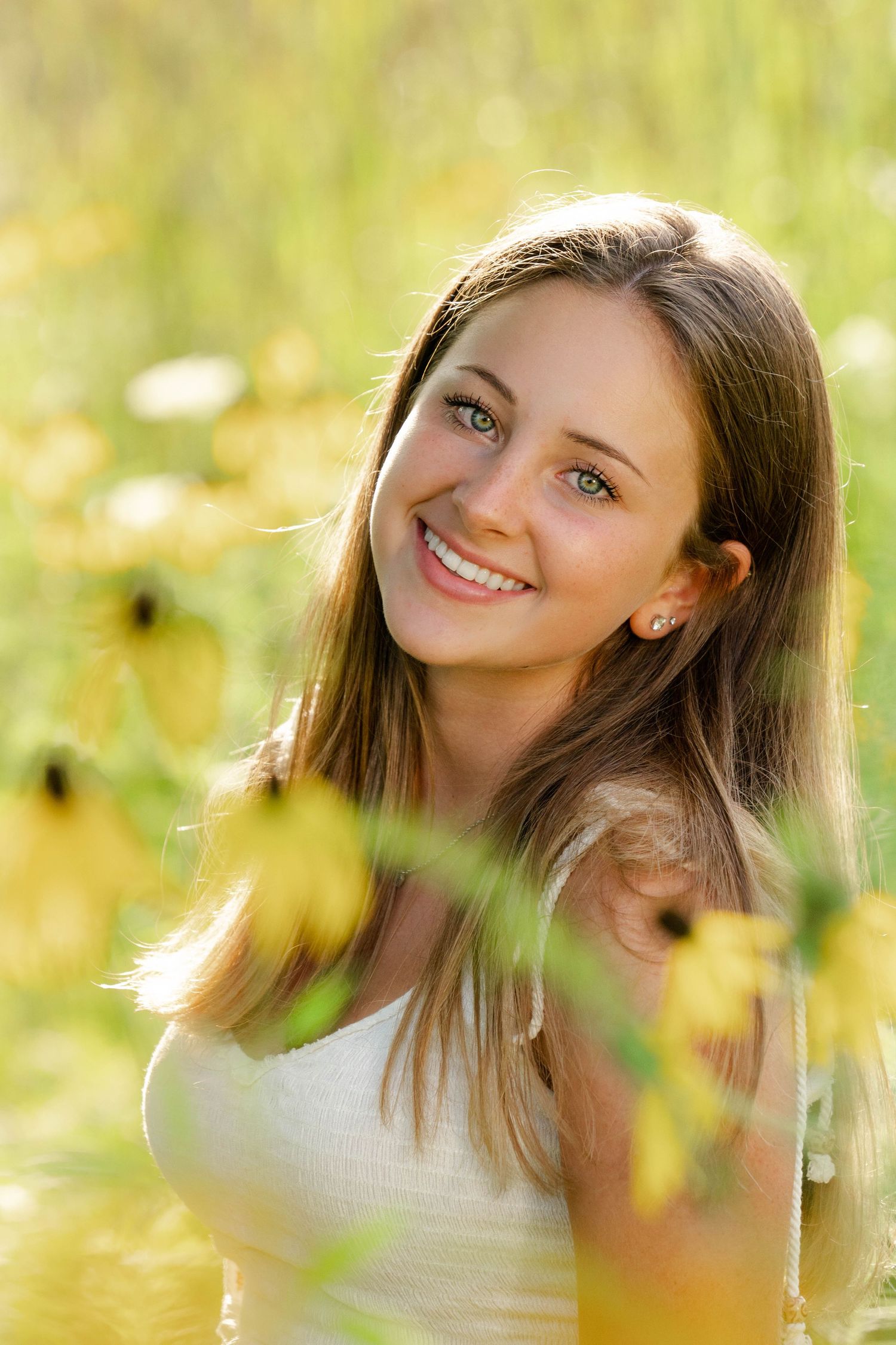 Person poses cheerfully among yellow wildflowers in natural sunlight.