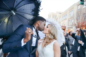 Romantic moment shared under a black umbrella during wedding celebration.
