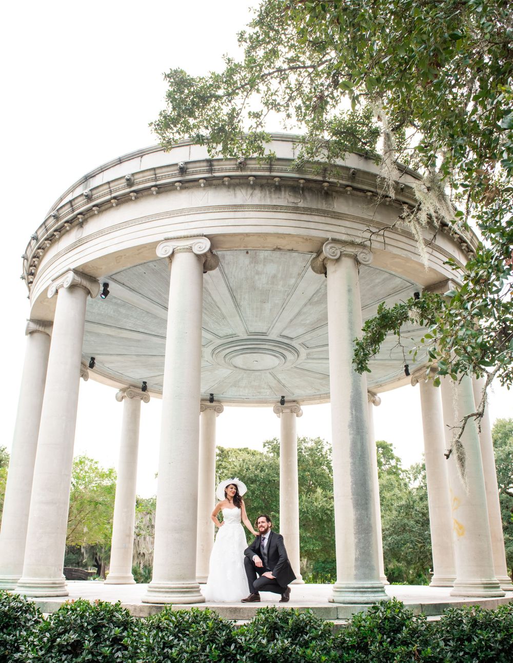Elegant white gazebo with classical columns provides romantic setting for wedding photo.