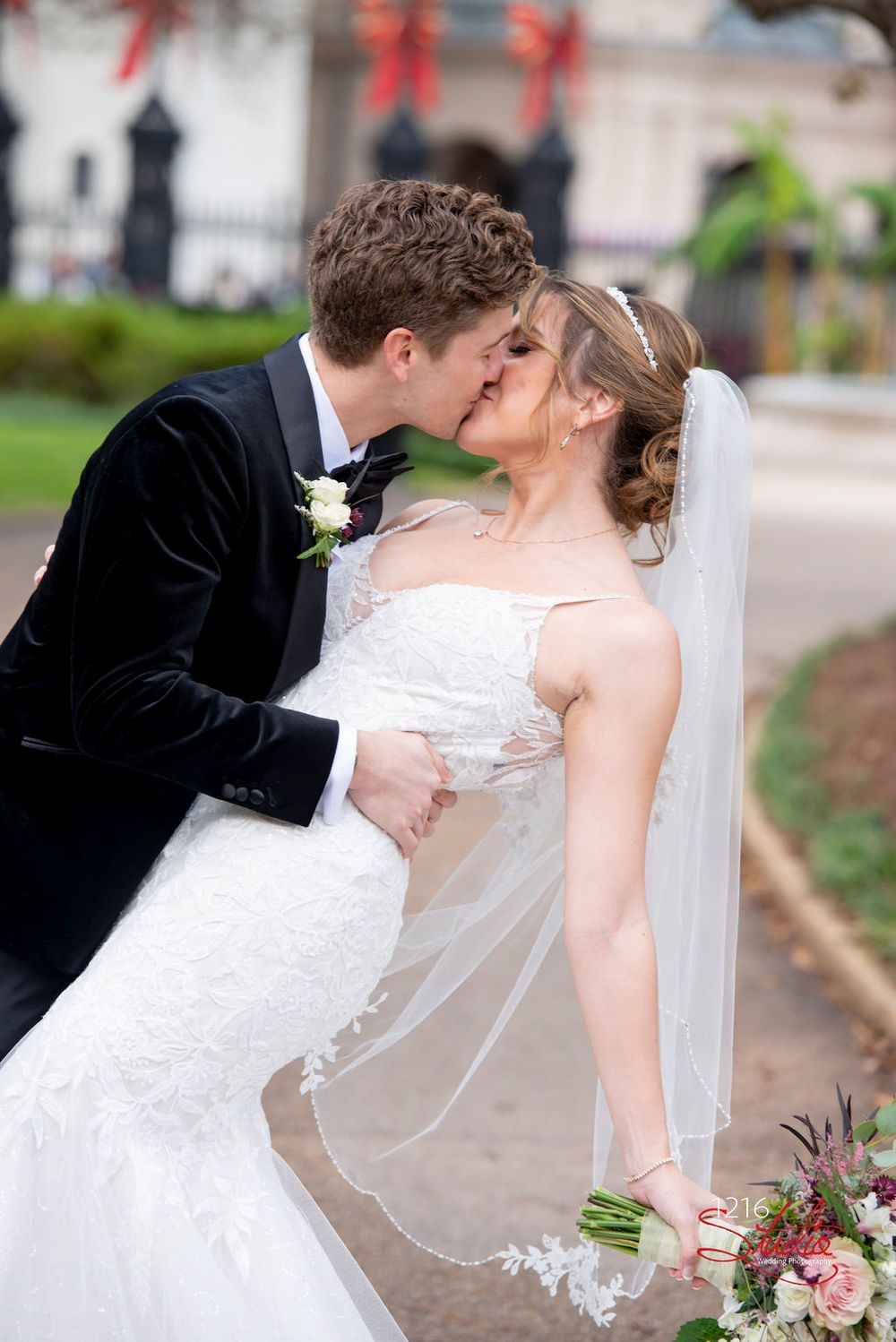 A romantic wedding moment captured outdoors with a flowing veil and floral bouquet.