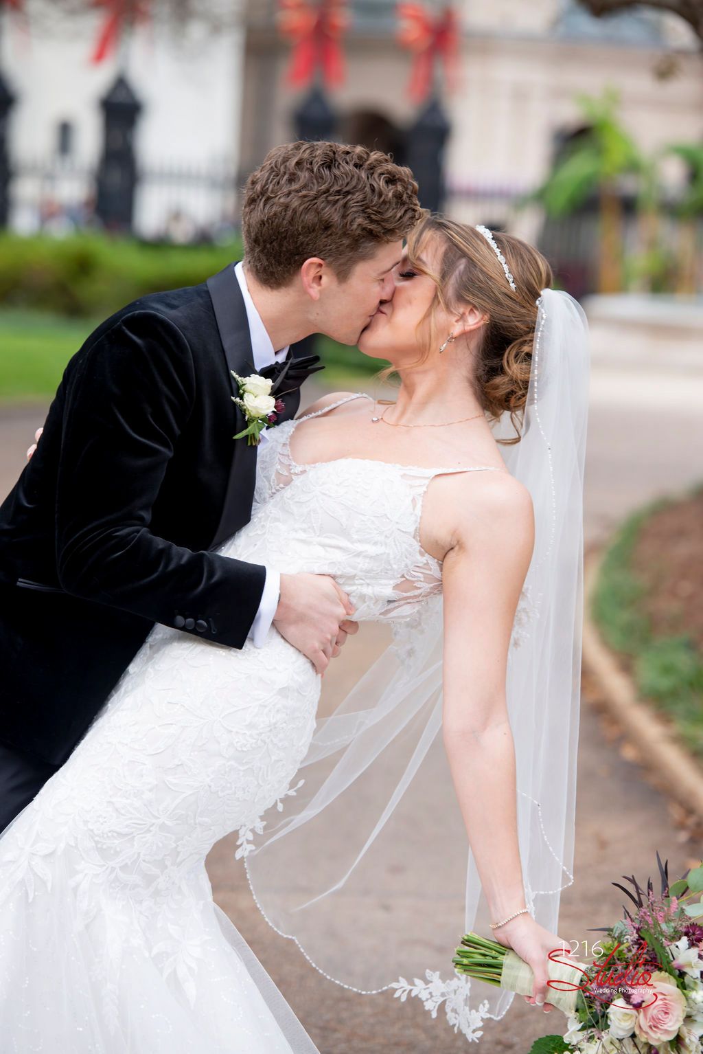 A romantic wedding moment captured outdoors with a flowing veil and floral bouquet.