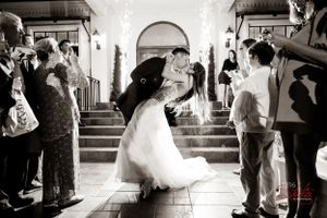 Black and white photo capturing a joyful wedding exit moment with guests creating a celebratory tunnel.