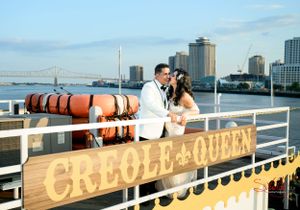 A romantic moment aboard the Creole Queen riverboat with a city skyline backdrop.