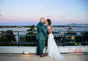 A sunset waterfront wedding portrait with a bridge visible in the background.