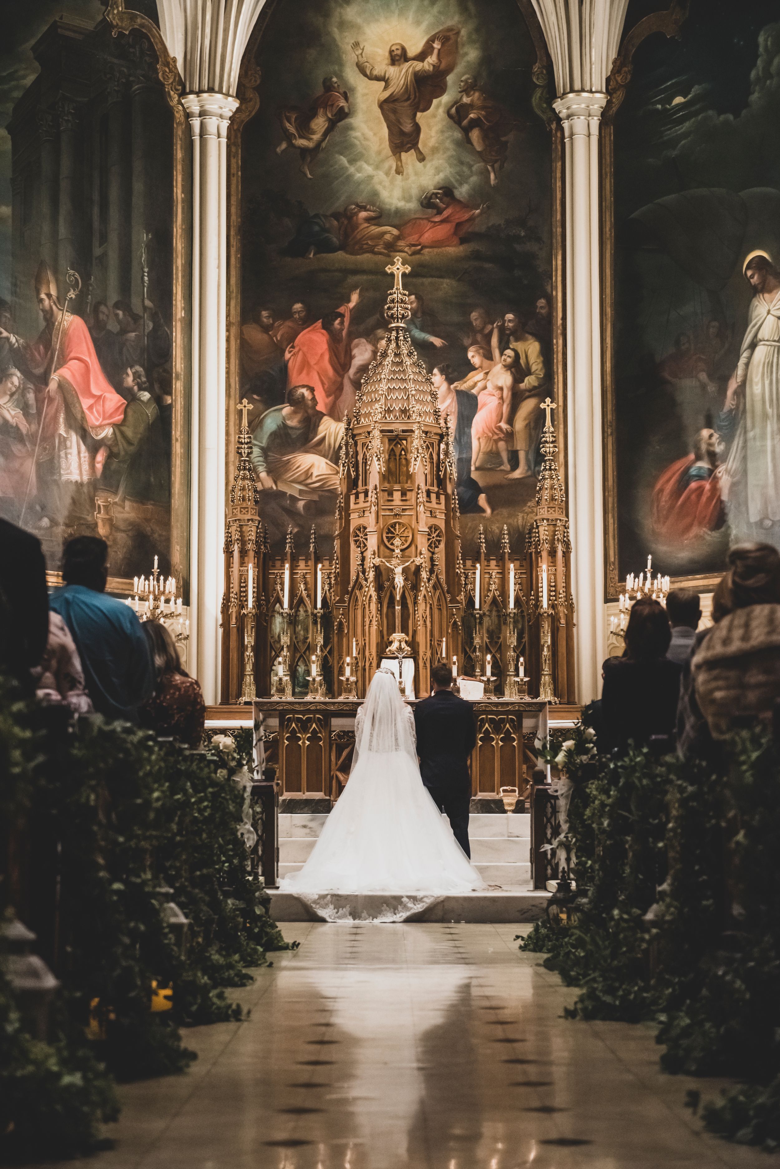 A cathedral wedding ceremony with ornate altar and religious artwork in dramatic lighting.
