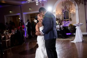 Couple shares intimate first dance moment on illuminated ballroom floor at reception.