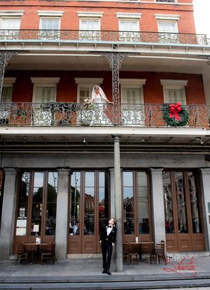 Wedding photo at historic New Orleans building with iron balconies and holiday wreath.