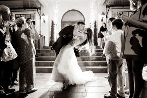 A joyful wedding celebration moment captured in black and white under an arched hallway.