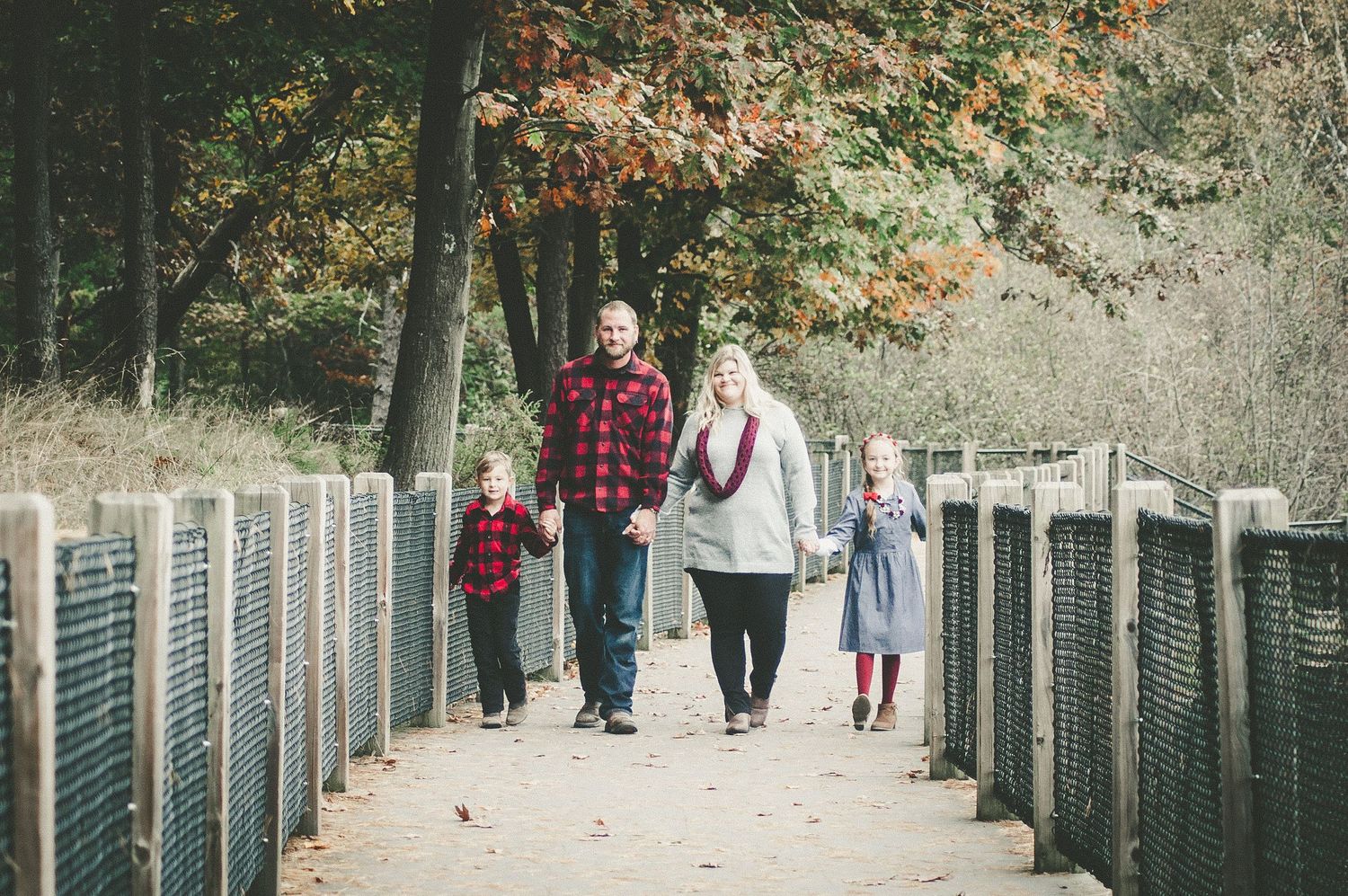A family walking together on a suspended bridge during autumn.