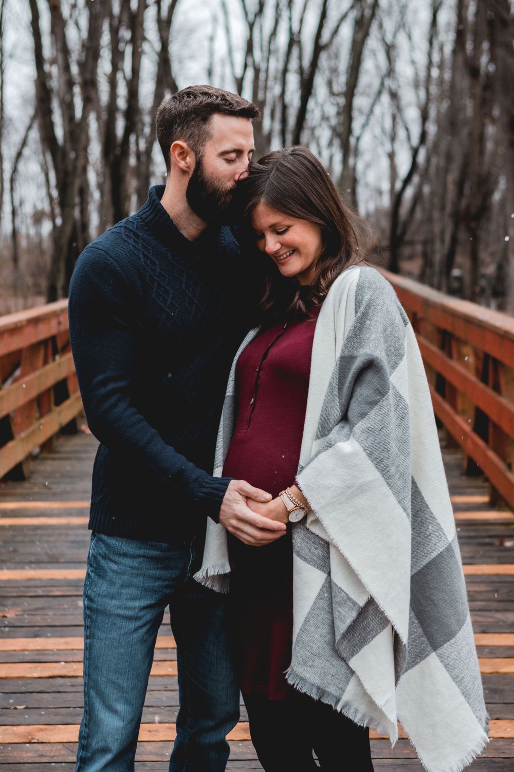 Couple sharing tender moments on wooden bridge during autumn photoshoot.
