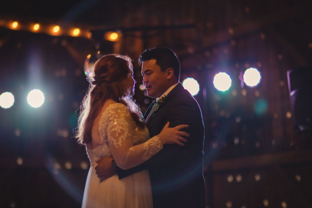 A couple shares their first dance at their wedding reception with bokeh lights in the background.