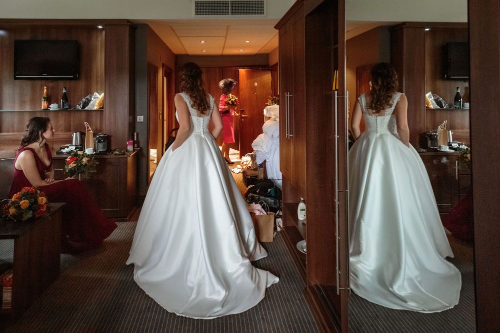 bride with her hands in the pockets pf her wedding dress reflected in the full length wardrobe mirror