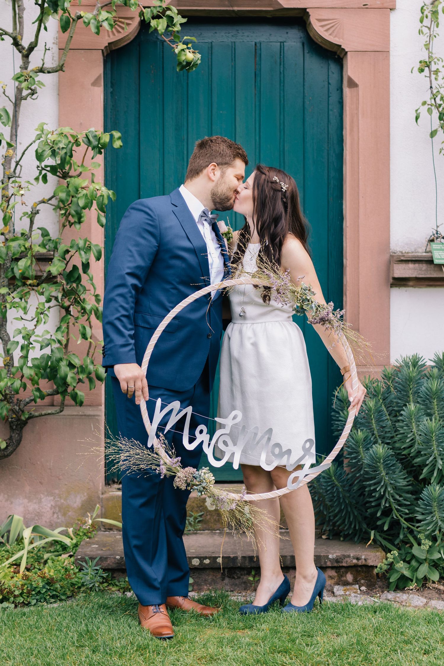 Hochzeitsfotografie - Brautpaar mit Mr und Mrs Bogen. Kuss im Hermannshof Weinheim.