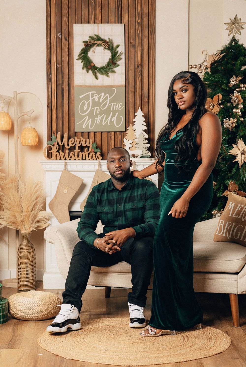 Couple holding hands in stylish outfits beside Christmas tree and holiday decorations.