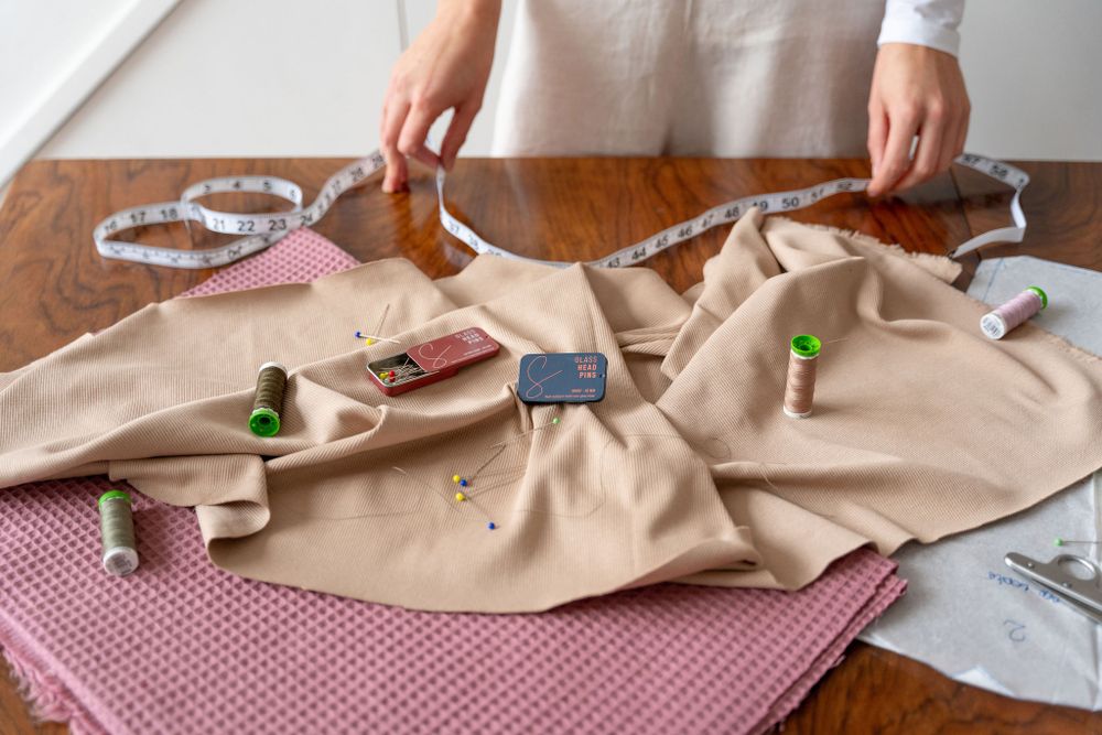 Overhead view of sewing project with spools of thread and scissors on beige fabric.