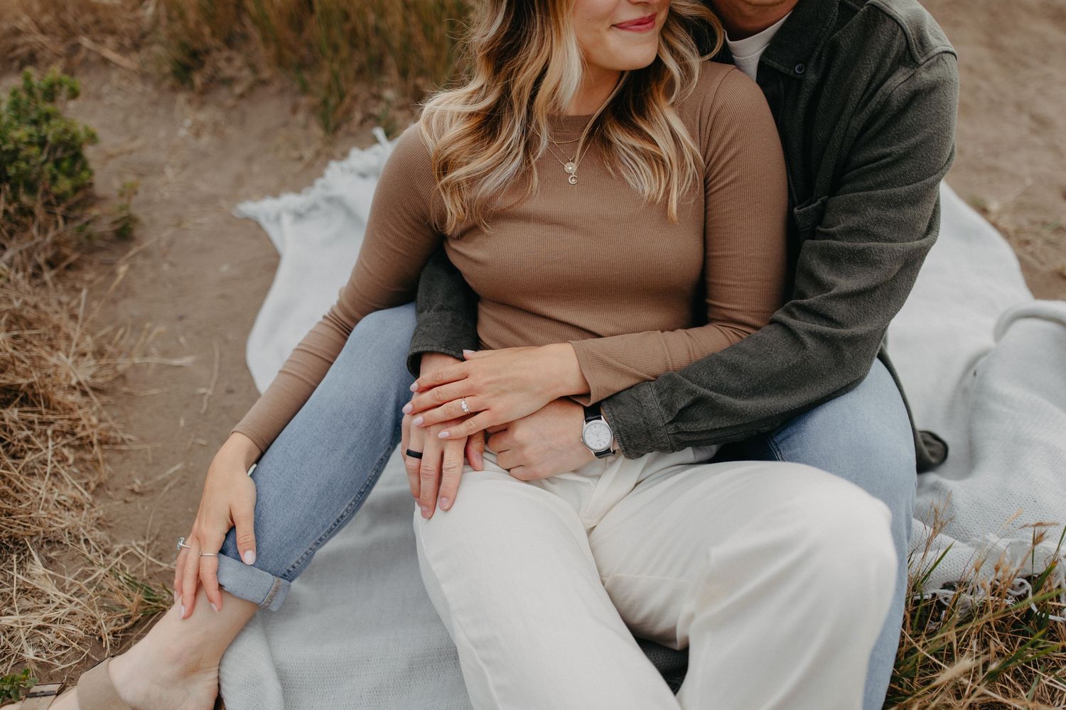 Couple sharing an intimate moment on a blanket outdoors.
