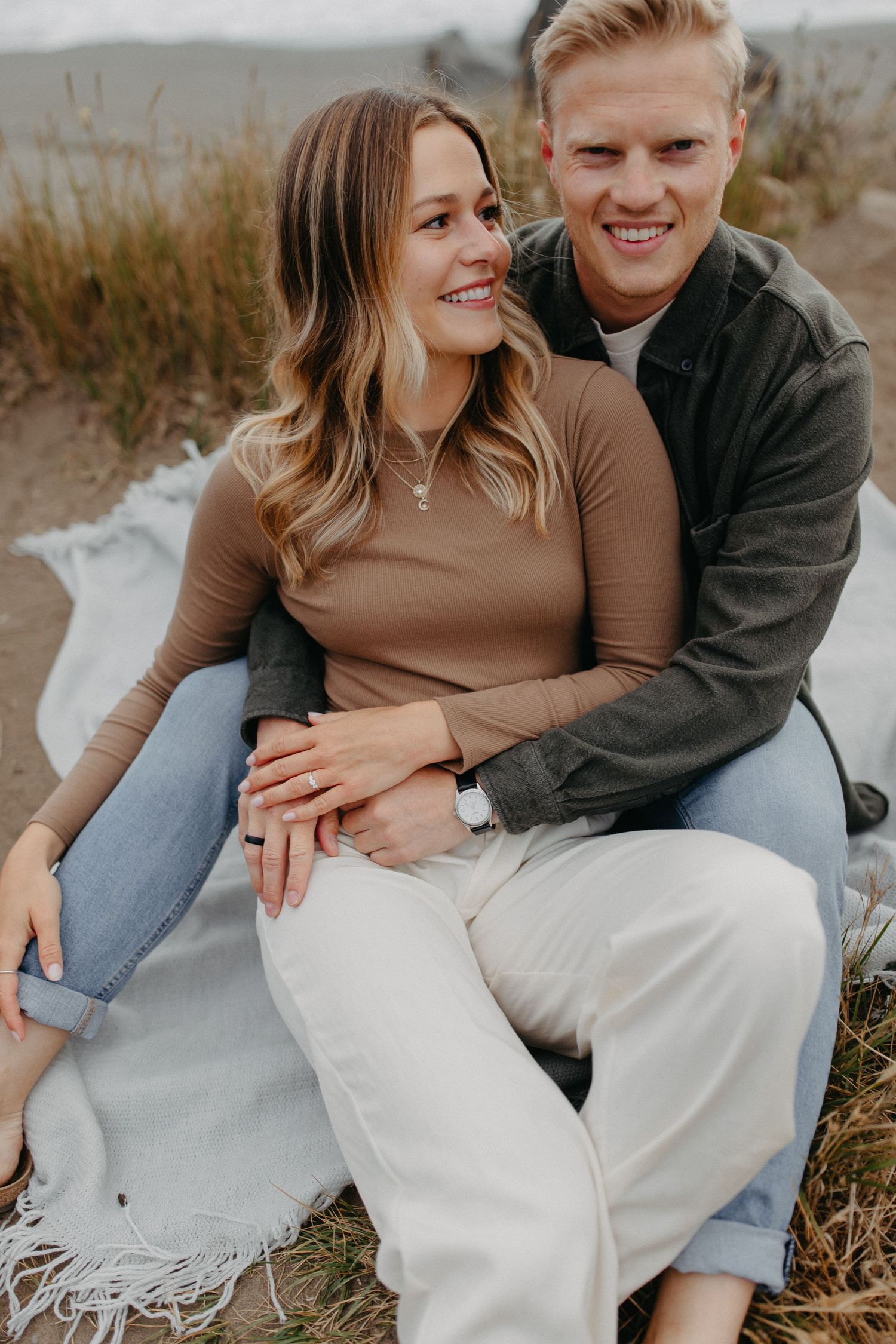 Happy couple in casual attire sharing intimate moment on coastal bluff.