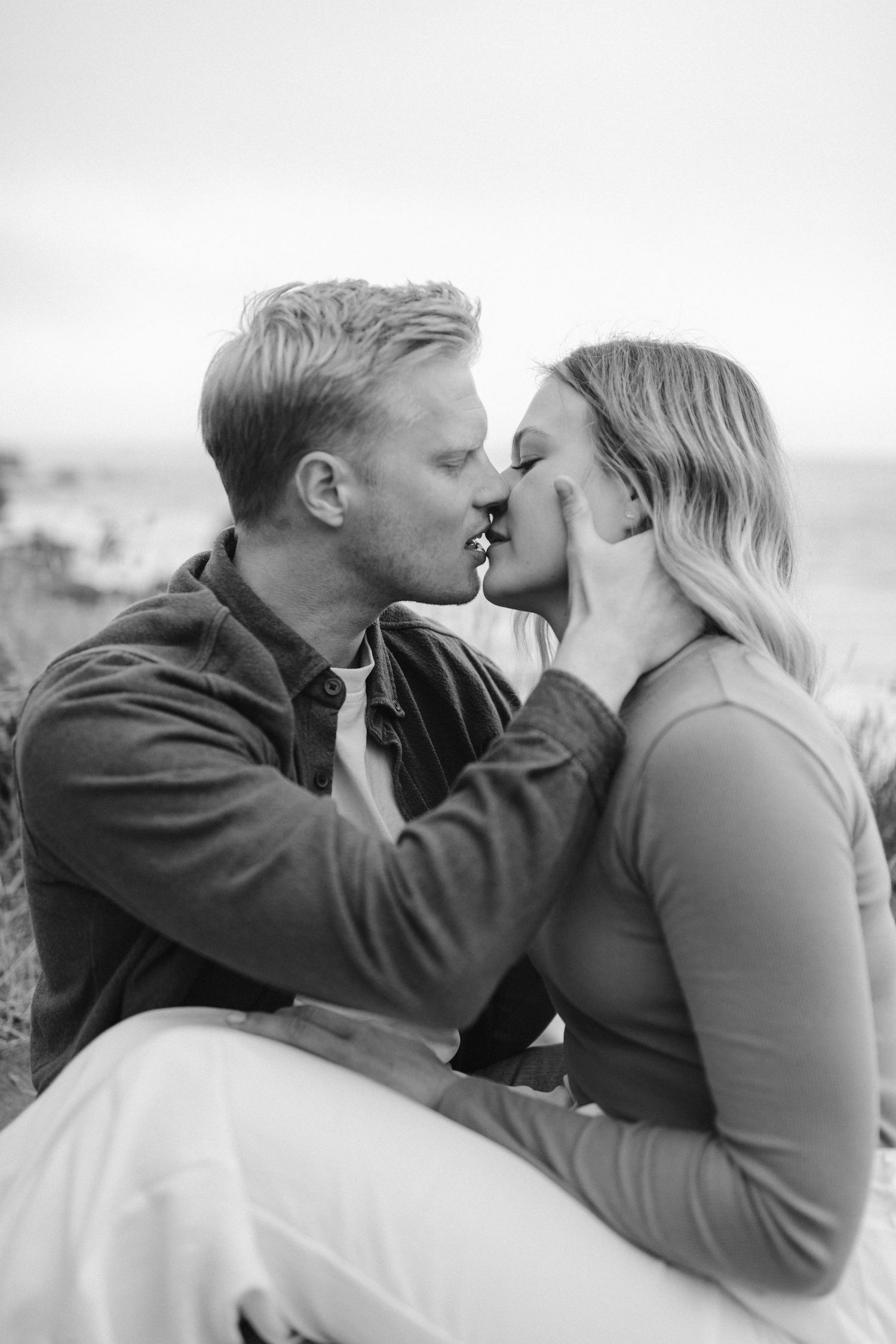 Black and white close-up of intimate moment between couple on coastal setting.