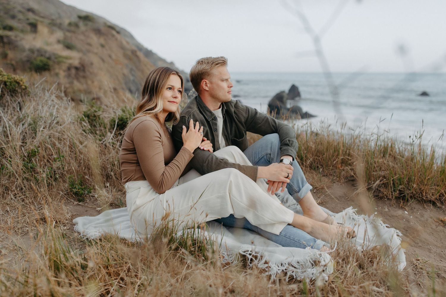 A couple enjoying a picnic on coastal cliffs overlooking the ocean.