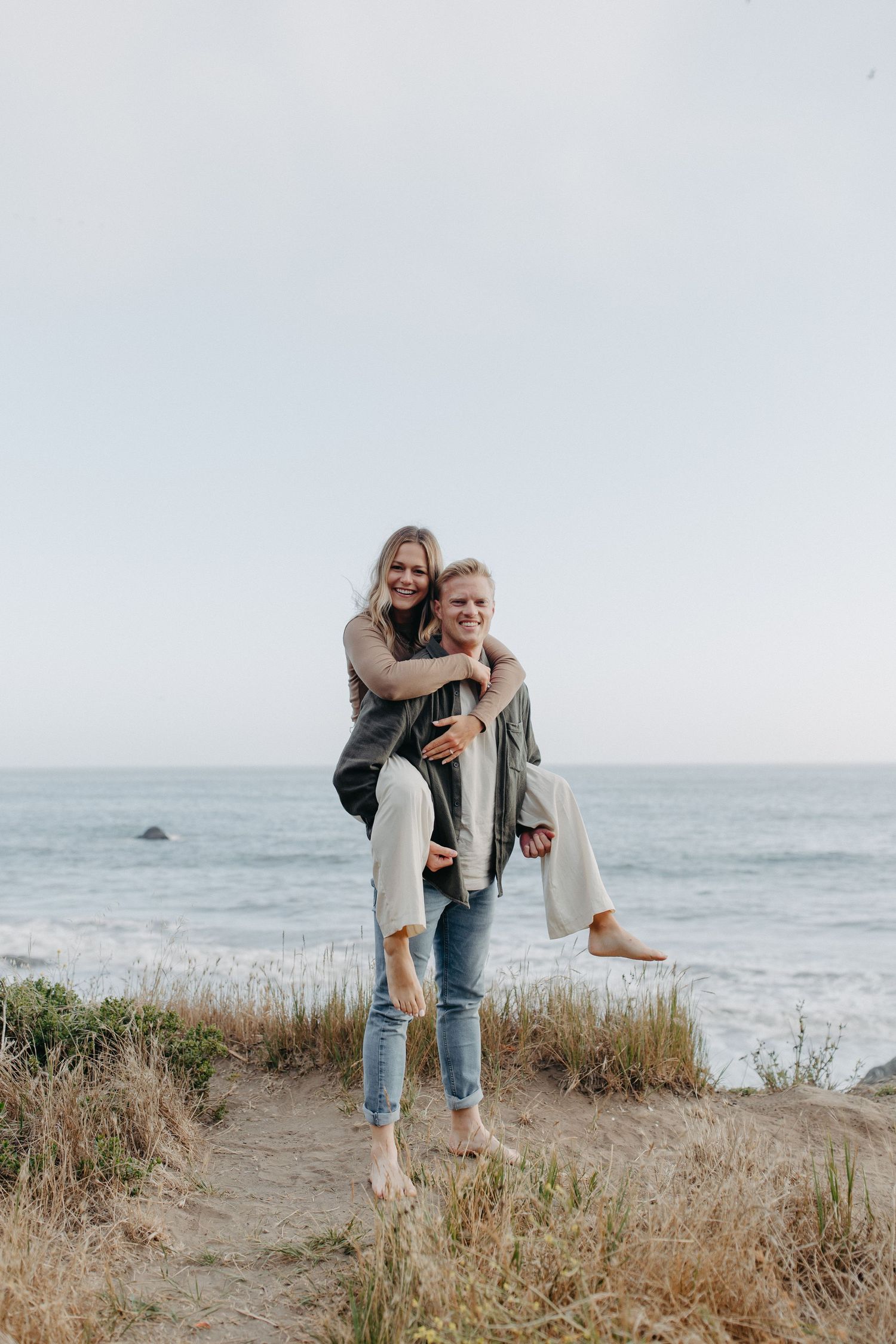 A joyful piggyback ride moment captured against the ocean landscape.
