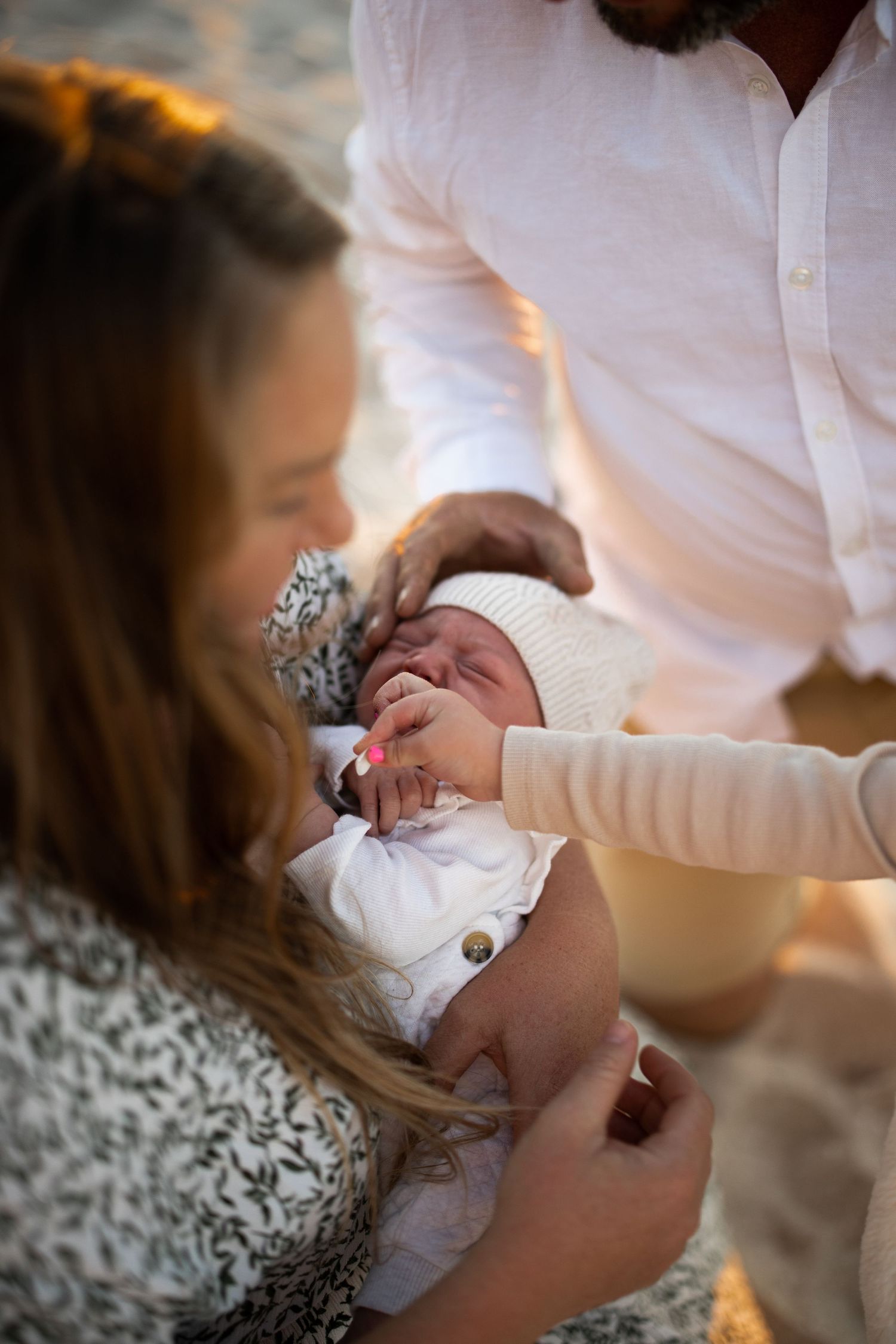 Tender moment of a newborn baby being held and cradled in white clothing.