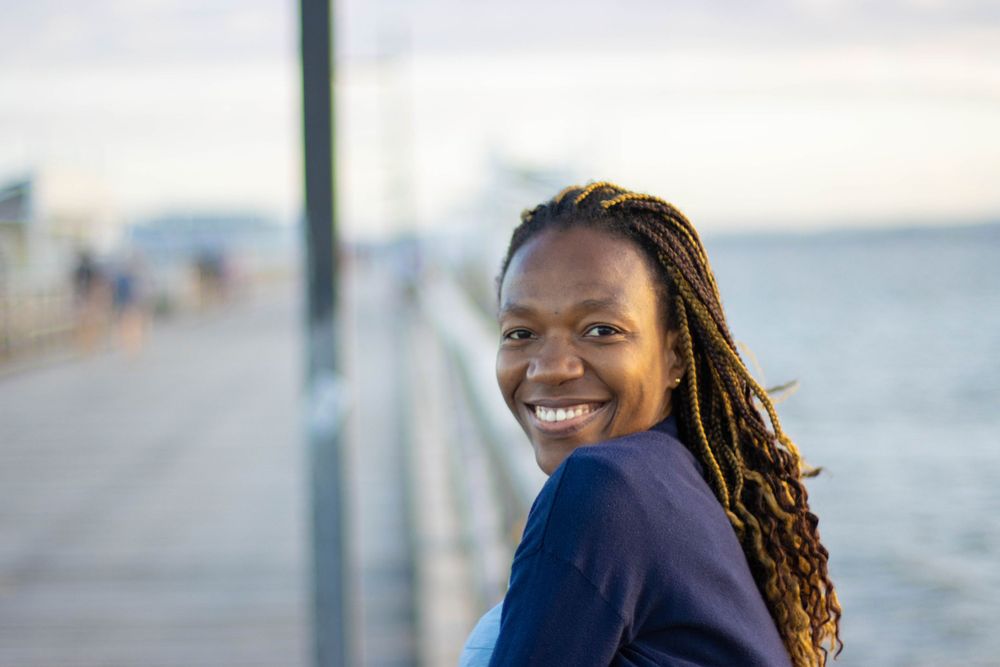 A bright outdoor portrait captured on a waterfront pier during golden hour.