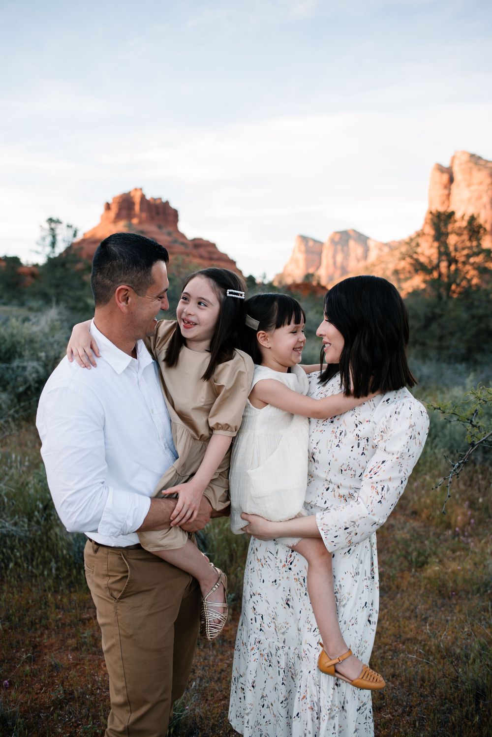 A romantic photoshoot in front of red rock formations during golden hour in a desert landscape.