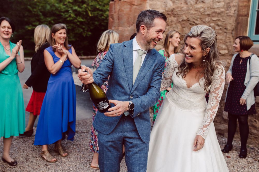 Wedding party celebrates with confetti toss outside historic stone venue.