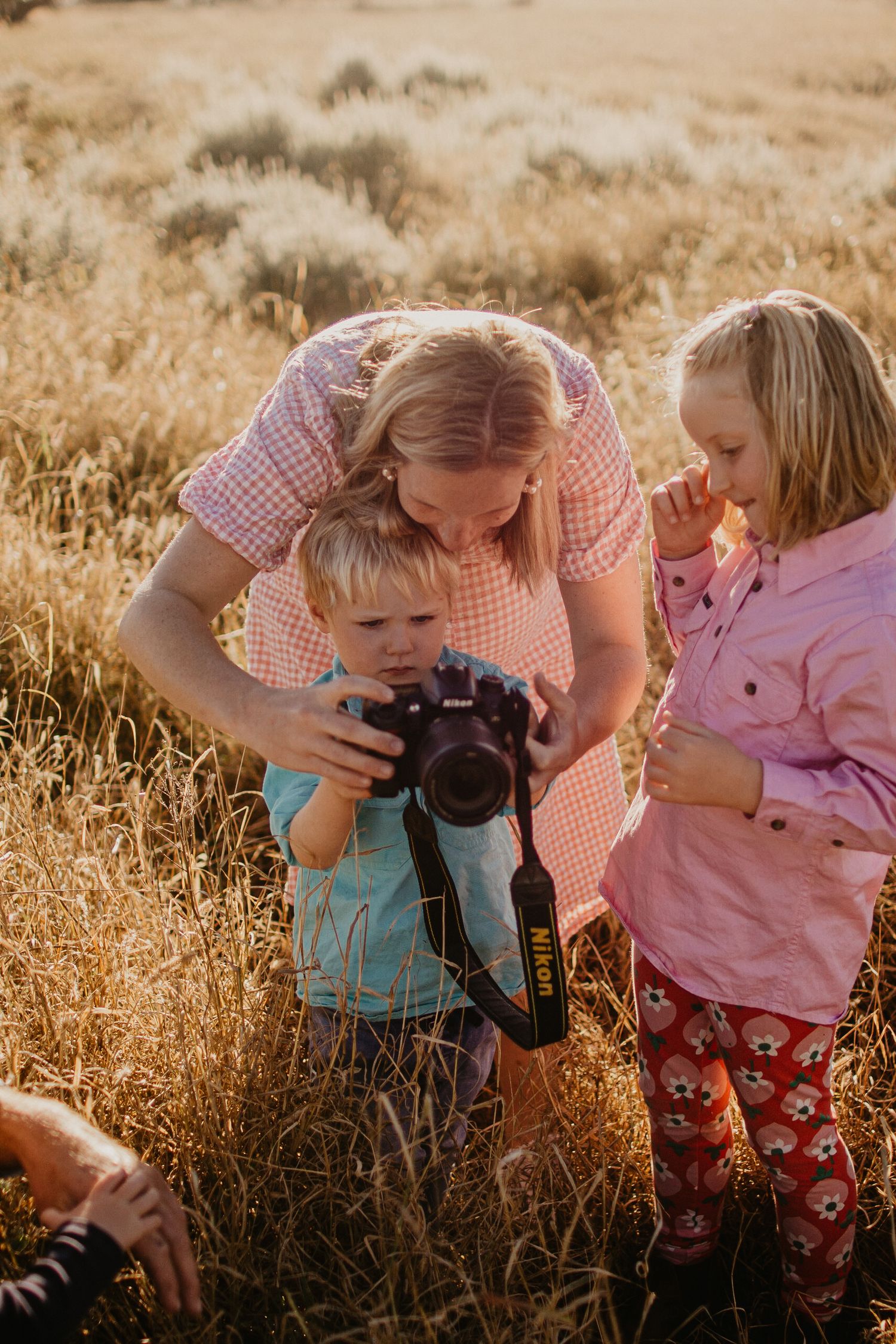 Mum in paddock with kids showing them how to use the camera