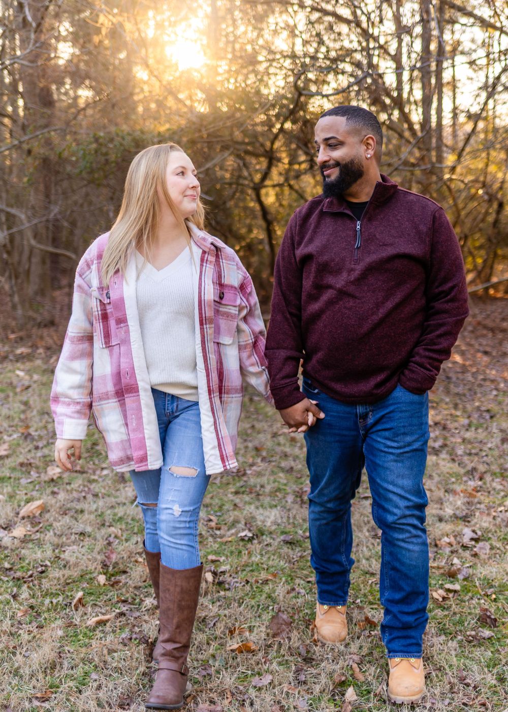 A couple takes a romantic autumn walk together through fallen leaves at sunset.
